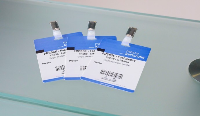 Close-up of three press passes for a trade show at Messe Karlsruhe.