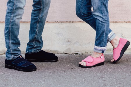 Foto von den Beinen zweier Personen, die Varomed-Schuhe tragen. Beide Personen tragen Jeans und eine Person schwarze, die andere Person rosa Schuhe.