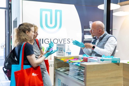 Exhibitor shows visitors disposable gloves at his stand.