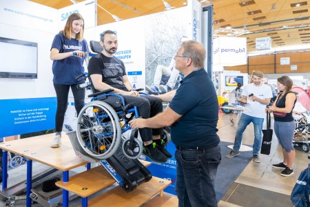 Ein Rollstuhlfahrer testet an einem Stand einen Treppenlift für Rollstuhlfahrer.