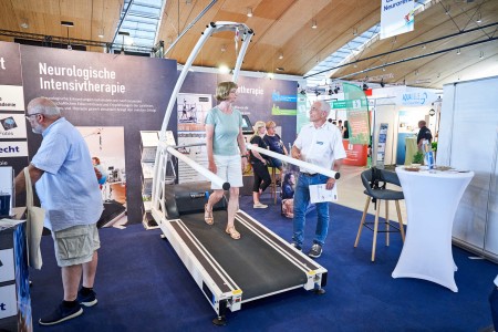 A trade fair visitor tests a treadmill at an exhibition stand.